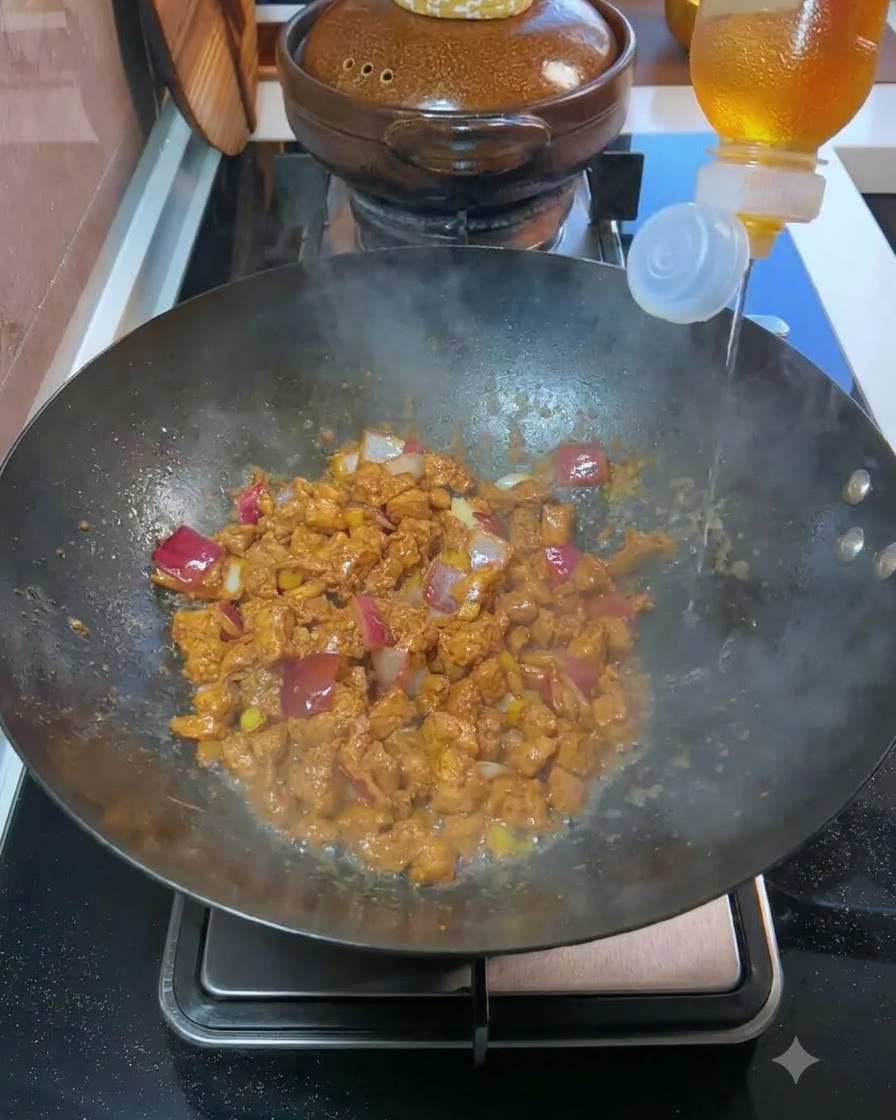 Cooking wine being poured from a bottle into a wok containing cooked meat and diced onions.