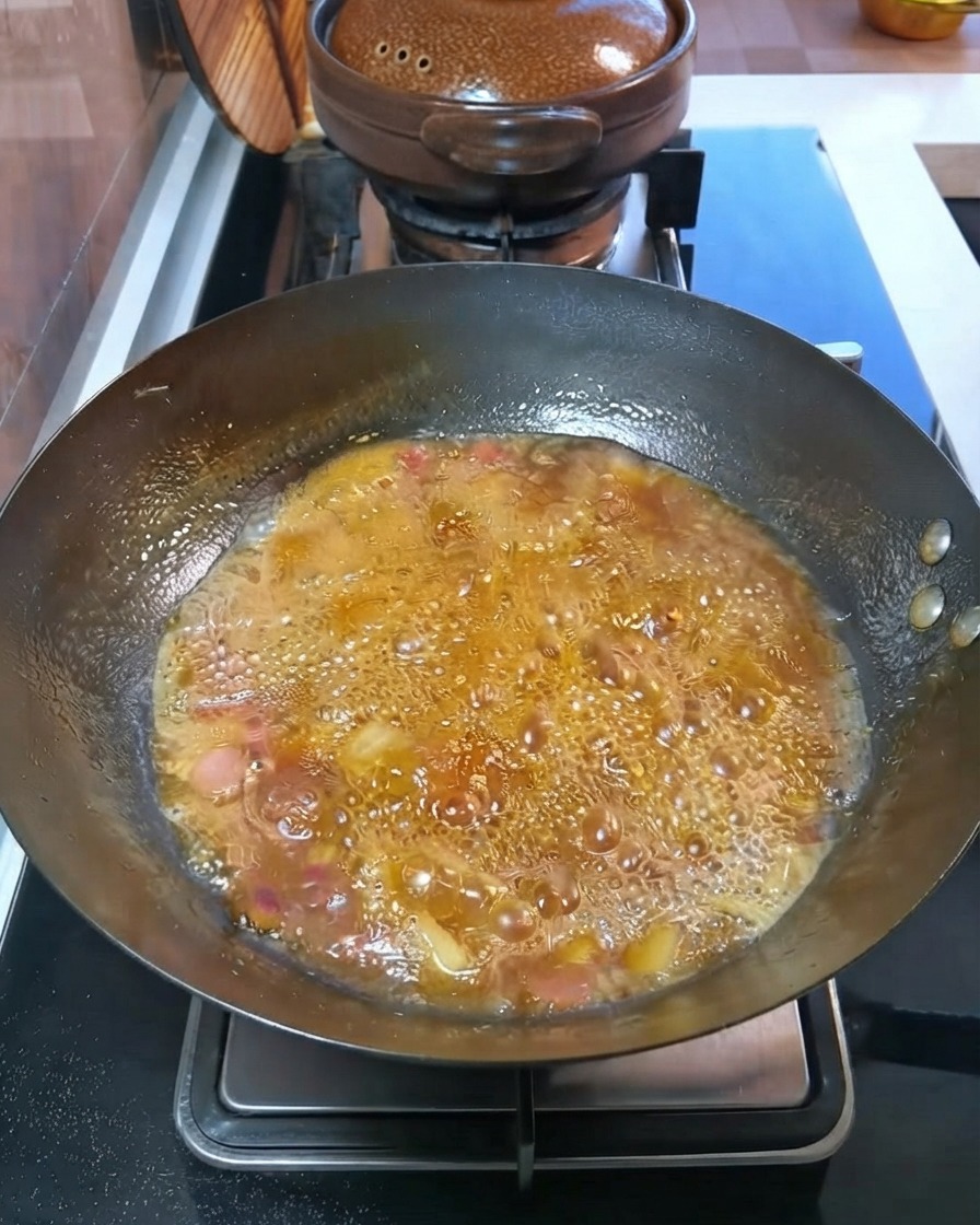 Diced potatoes and carrots simmering in a bubbling broth inside the wok.