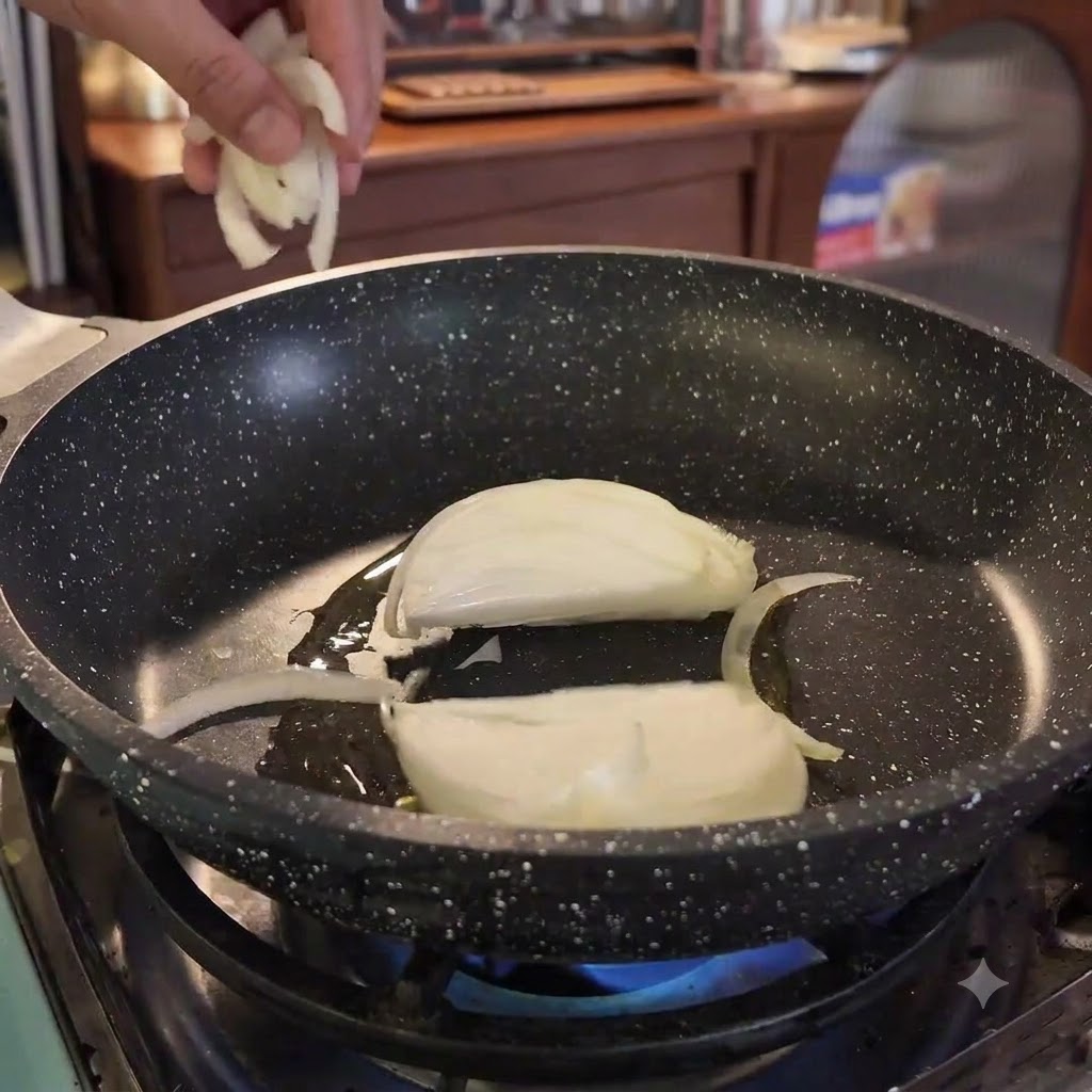 Onion slices being added into a hot skillet with oil over a blue flame.