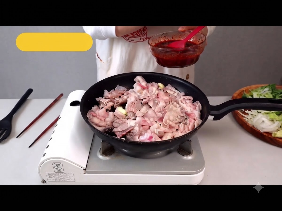 Thinly sliced pork belly cooking in a pan with some fat rendered out.