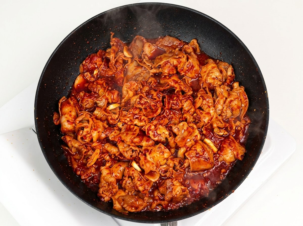 Shredded white onion added into the pan with saucy stir-fried pork.