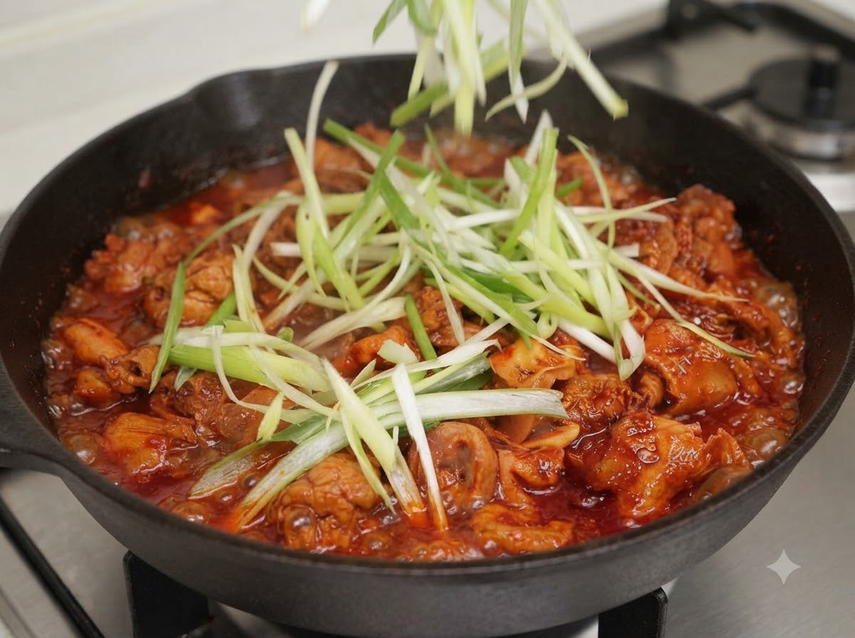 Shredded green onions and green chili strips being added on top of the pan mixture.