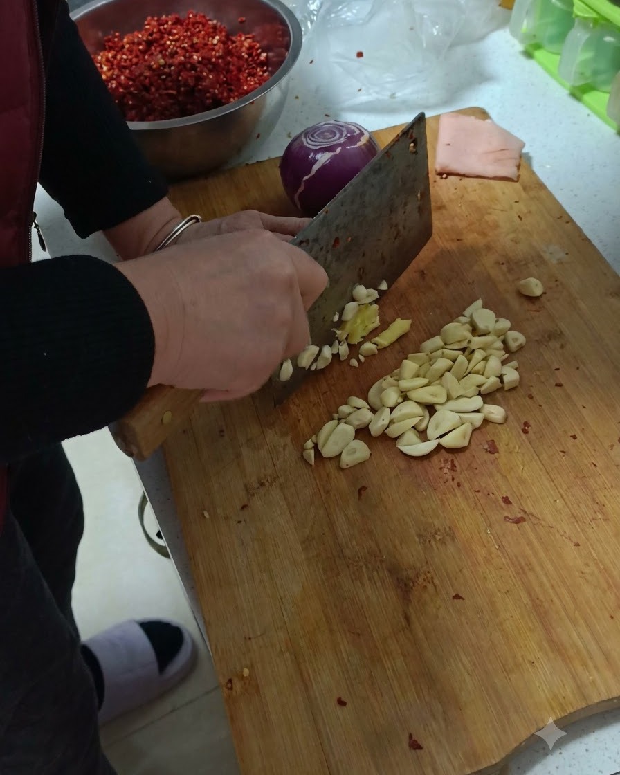 Garlic, ginger, and a purple onion being minced on a wooden cutting board.