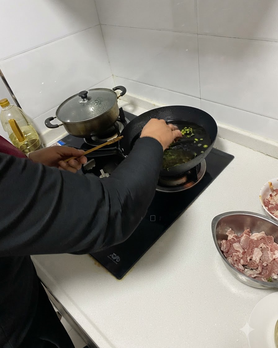 Minced aromatics being added into hot oil in a wok using chopsticks.
