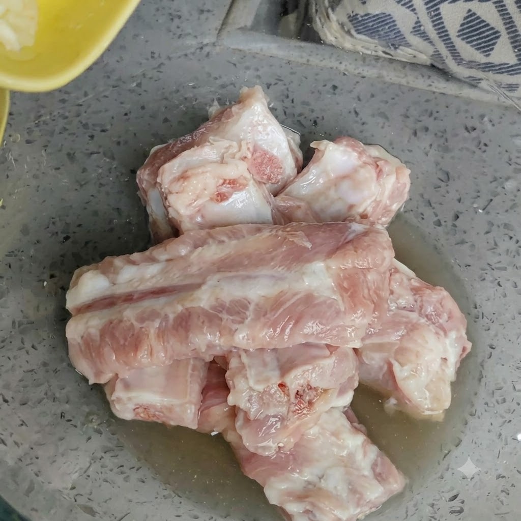 Bowl of raw pork ribs with freshly minced garlic added on top.