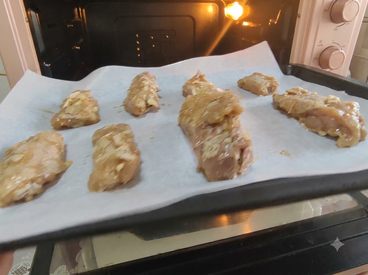Marinated pork ribs neatly arranged on parchment paper on a baking sheet ready for the oven.
