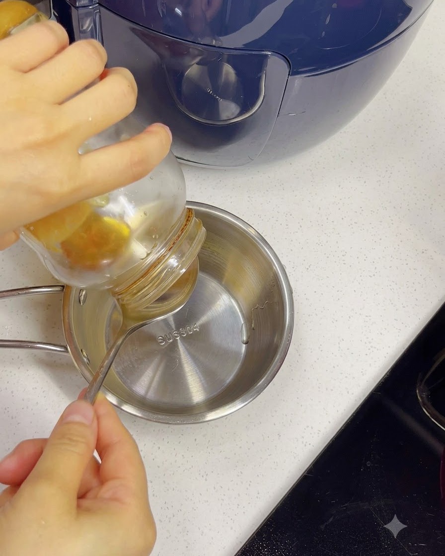 Honey being poured from a jar into a small stainless steel bowl with water using a spoon.