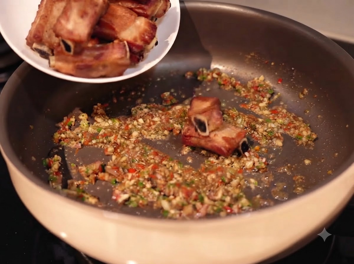 Spare ribs being added from a white plate into a pan filled with sautéed minced garlic, chilies, and spices.