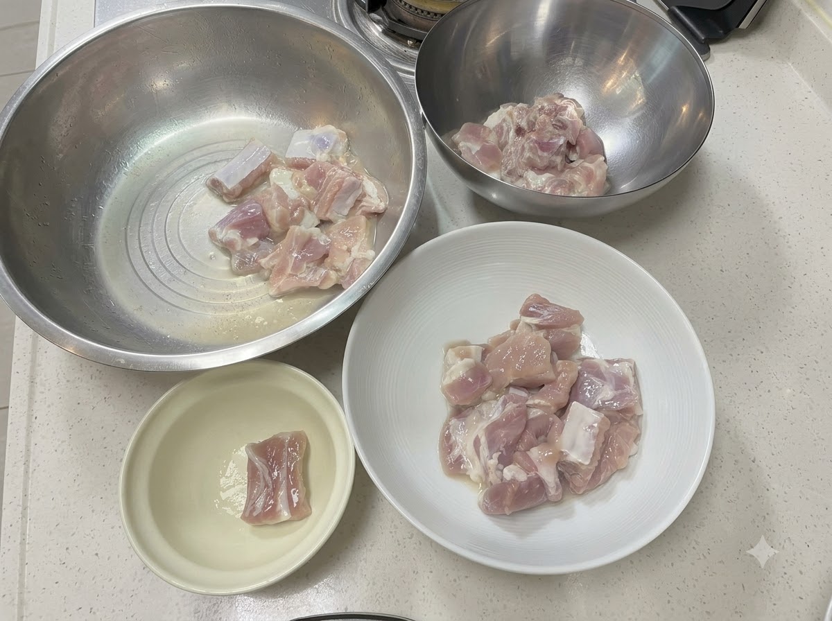 Pork rib pieces arranged in various metal and ceramic bowls on a white countertop.