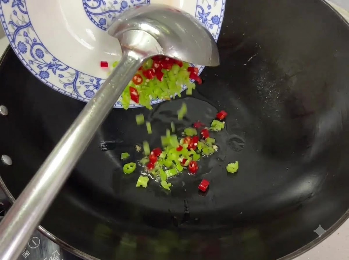 Red and green chili pieces being tipped from a plate into a wok with oil.