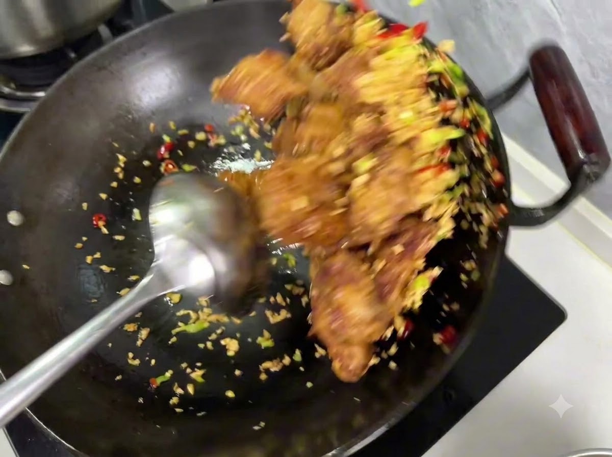 Salt and pepper seasoning being sprinkled over the mixture of ribs and garlic inside a wok.