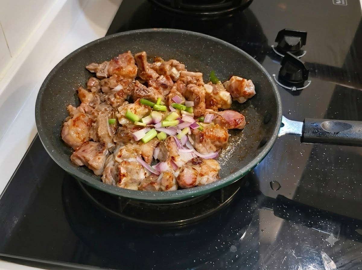 Chopped green onions and ginger spread over the pork ribs in the frying pan.