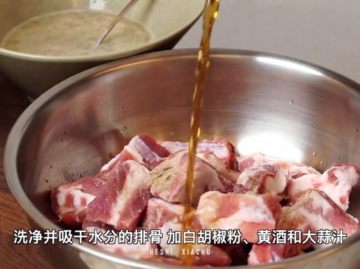 Yellow wine being poured from above into a metal mixing bowl filled with cut pork rib pieces sprinkled with white pepper powder.
