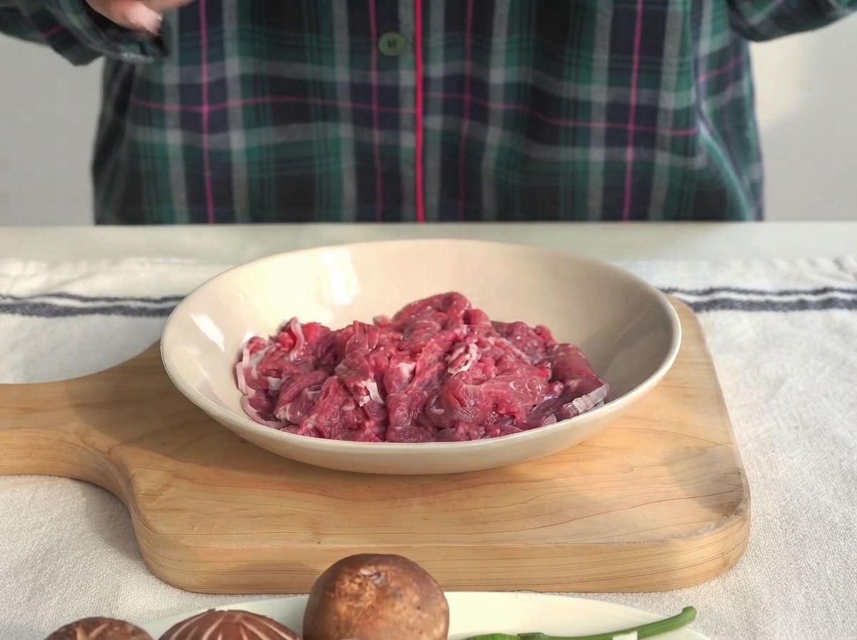 Beef tenderloin pieces in a shallow bowl being marinated with oyster sauce and cornstarch.