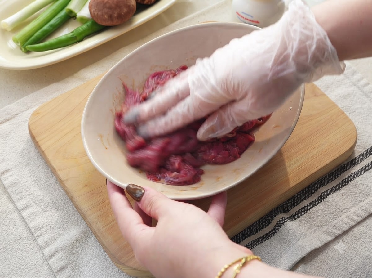 Onions, green chilies, and garlic being sliced on a wooden cutting board.