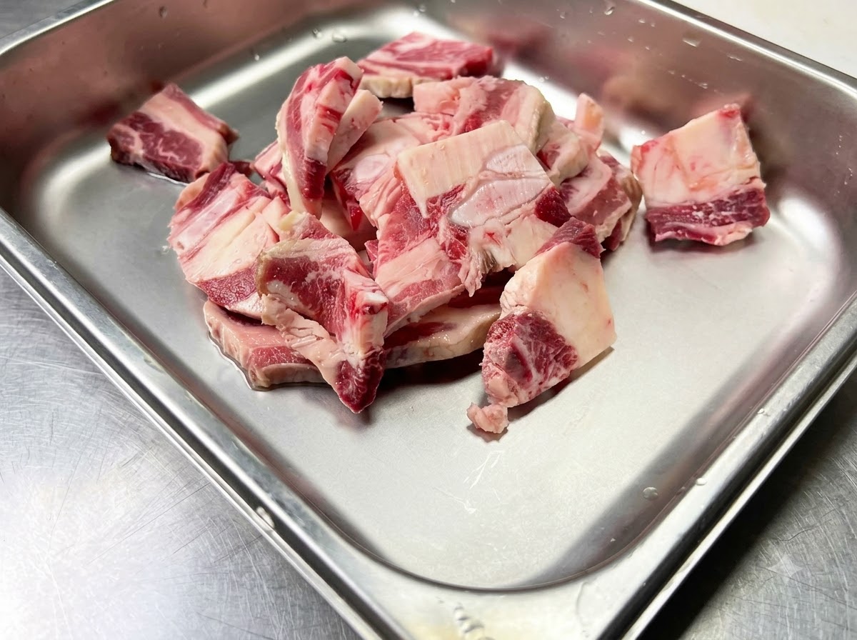 Raw beef short ribs placed inside a clean metal container ready for seasoning.