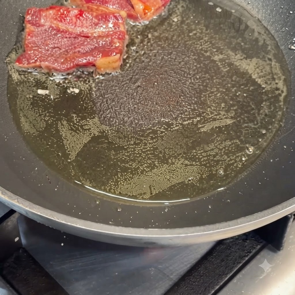 Marinated beef short ribs pan-searing in hot oil in a frying pan.