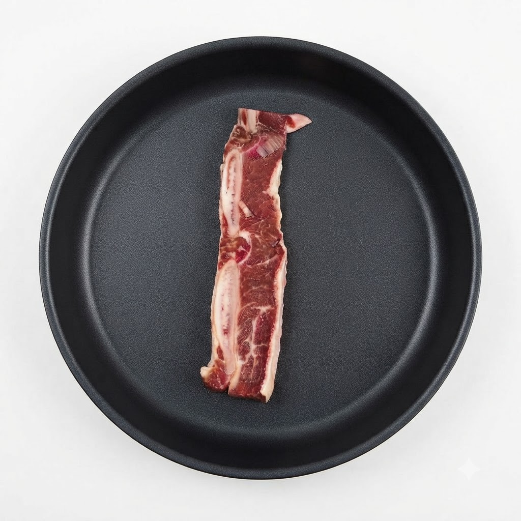 A single piece of marinated beef rib placed inside a dark pan.