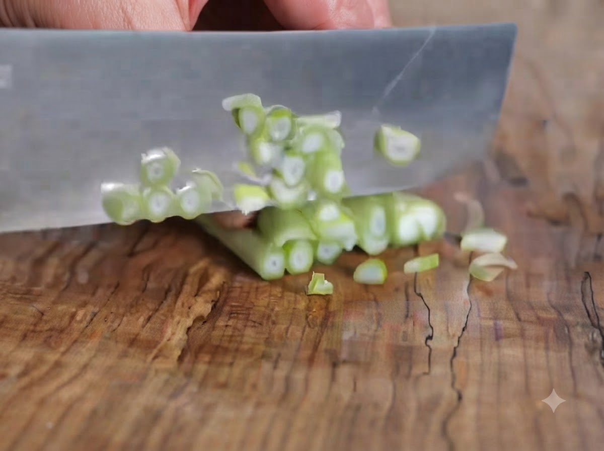 Green onions being sliced into small rounds on a wooden cutting board with a knife.