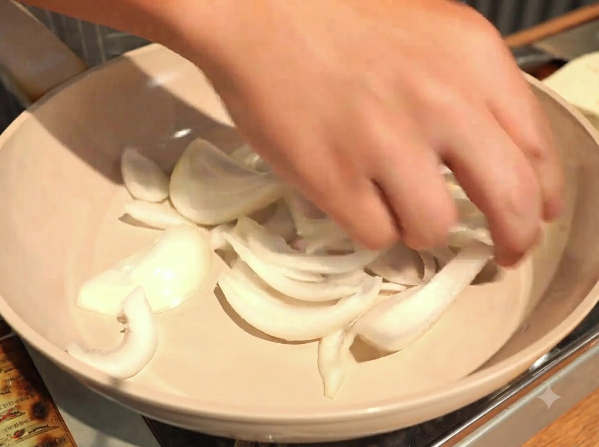 Spreading the sliced onions evenly across the bottom of a shallow cooking pan.