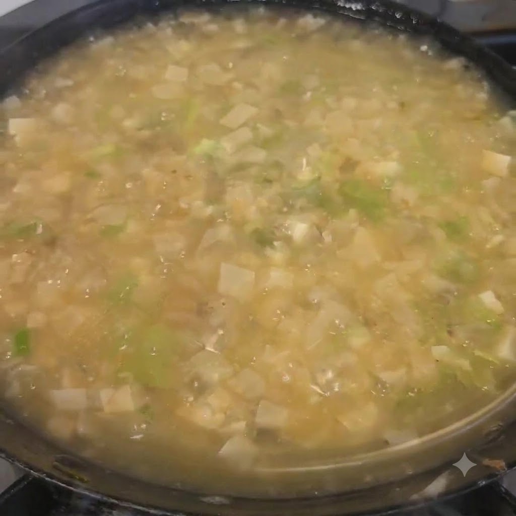 Chopped cilantro being sprinkled over the finished soup in the pot.