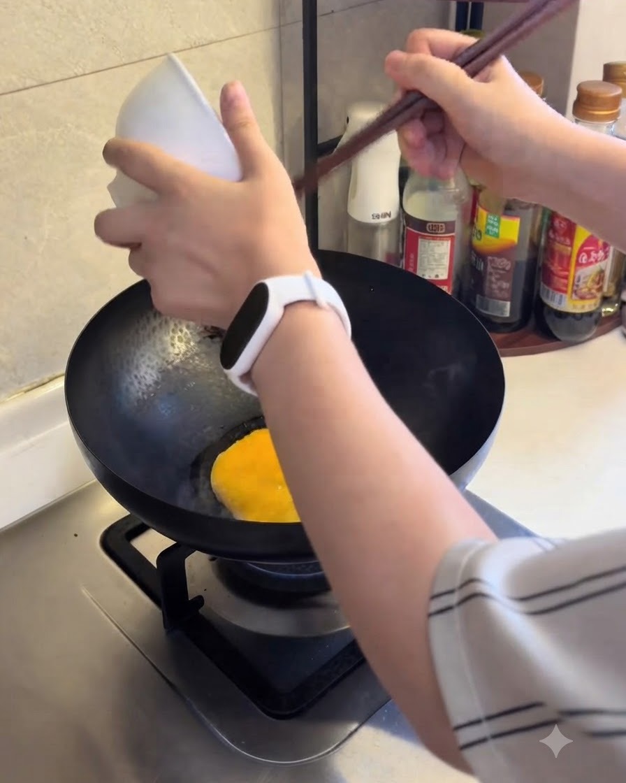 Beaten egg being poured into a hot pan to cook.