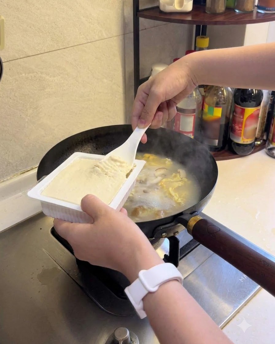 Soft tofu being added to the simmering soup.