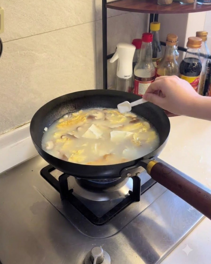 Salt and white pepper being sprinkled into the simmering tofu and mushroom soup.