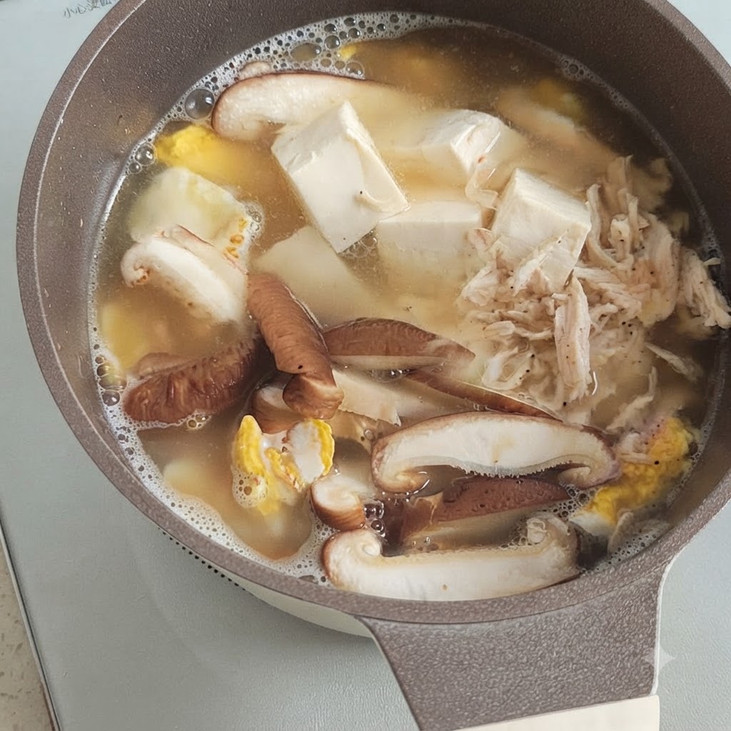 A small mound of dried shrimp sitting on top of simmering tofu, mushrooms, and egg in a pot of broth.