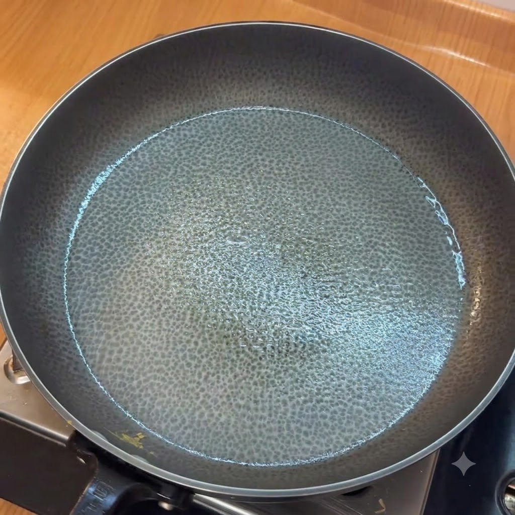 Minced garlic sautéing in a greased pan before adding chopped tomatoes.
