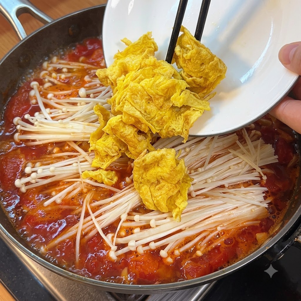 Cubed soft tofu pieces being added into the boiling soup pot with mushrooms and tomatoes.