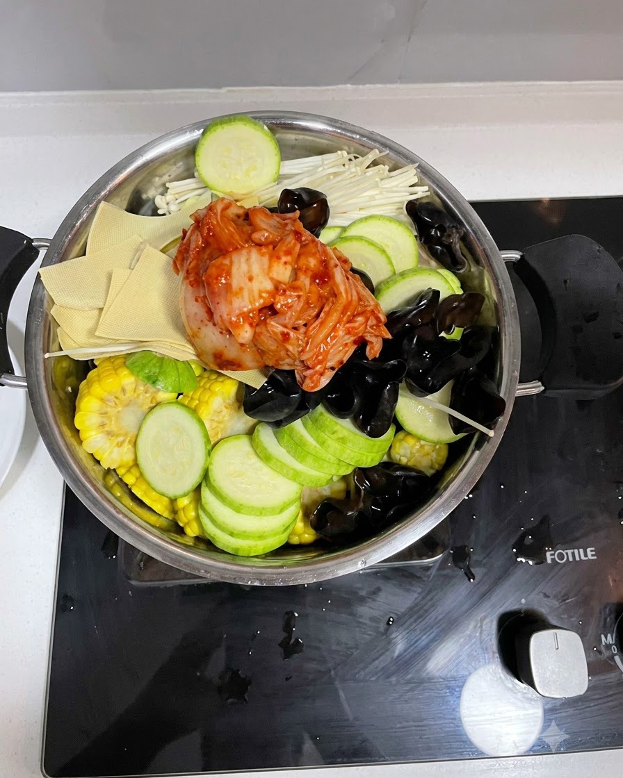 Pouring the prepared sauce mixture over the ingredients in the cooking pot.