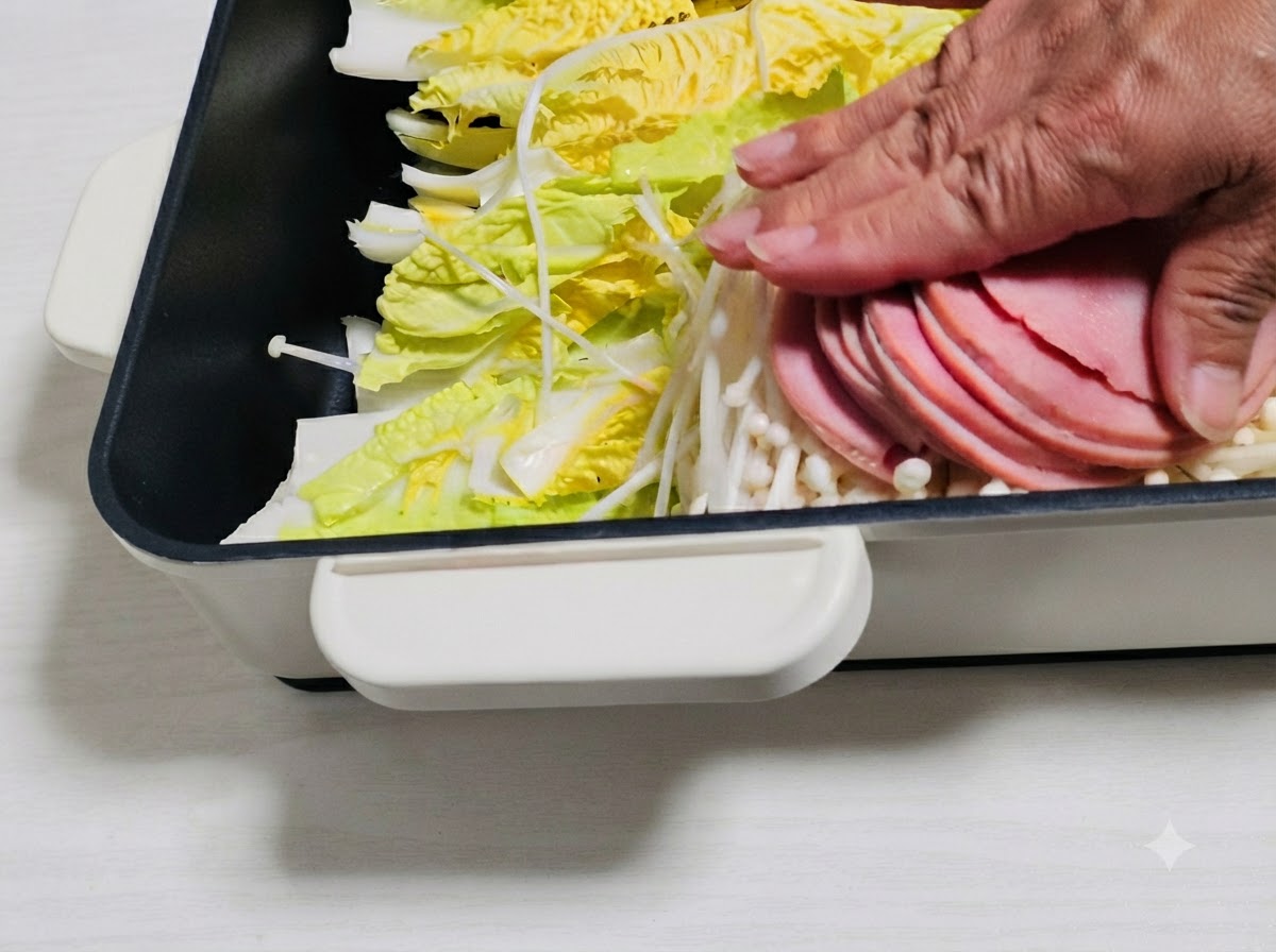 Ham slices and other ingredients being arranged over the vegetables in the pot.
