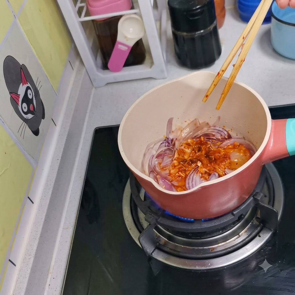 Kimchi and red onions being stirred together in the pot using wooden chopsticks.