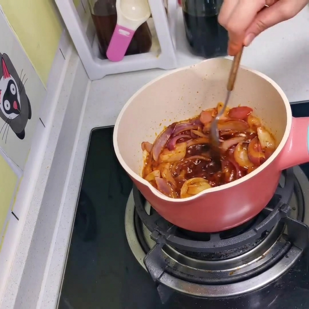 The sauce, onions, and kimchi being mixed together in the pot with a spoon.