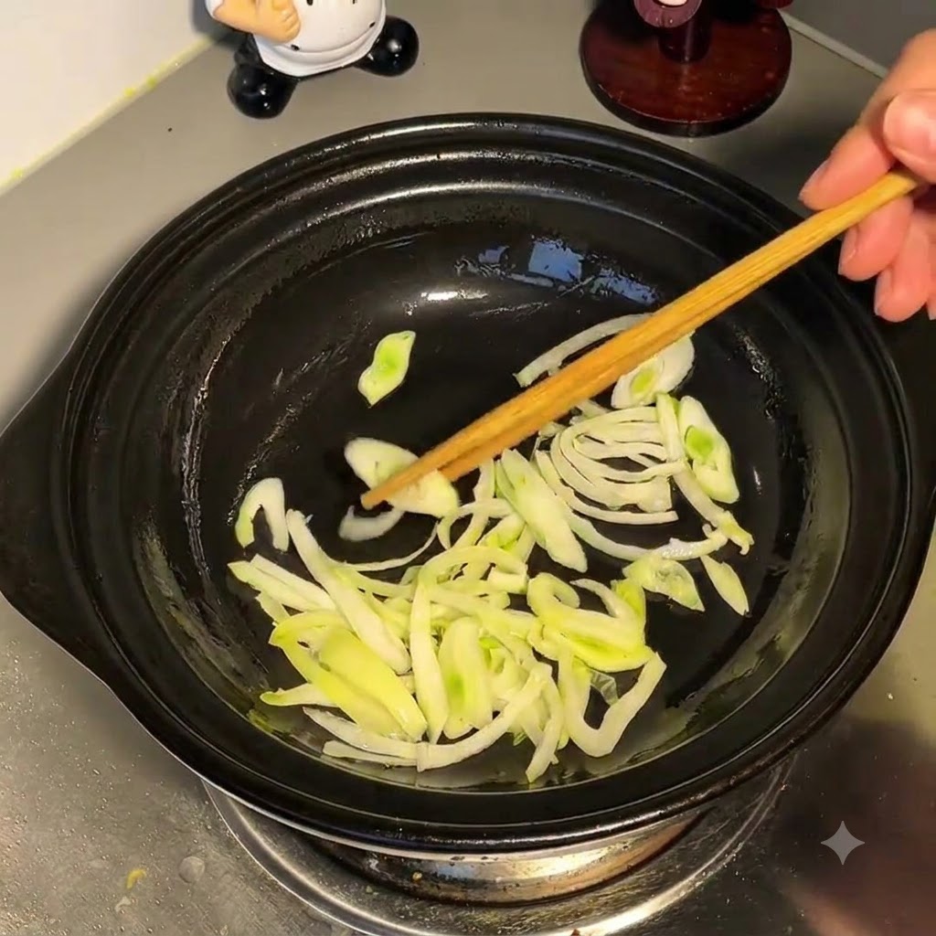 Water being poured from above into a pot containing sautéed green onions.