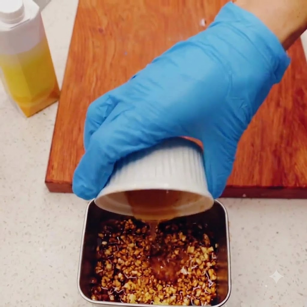 Honey being poured into a metal container with minced garlic and soy sauce.