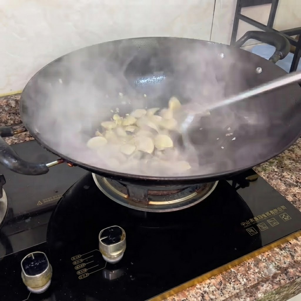 Cooking wine being added to a steaming wok of white clams during the stir-frying process.