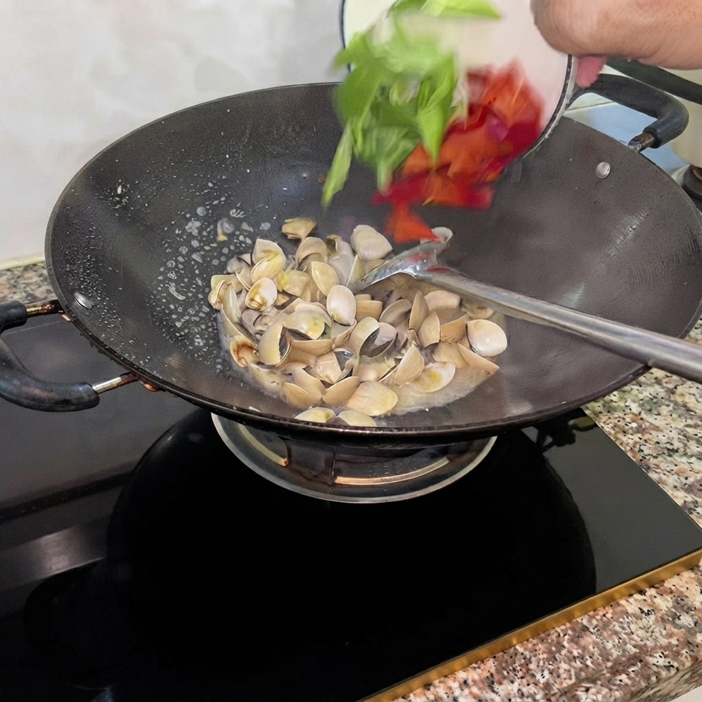 Slices of green and red peppers being tossed into the wok with stir-fried clams.