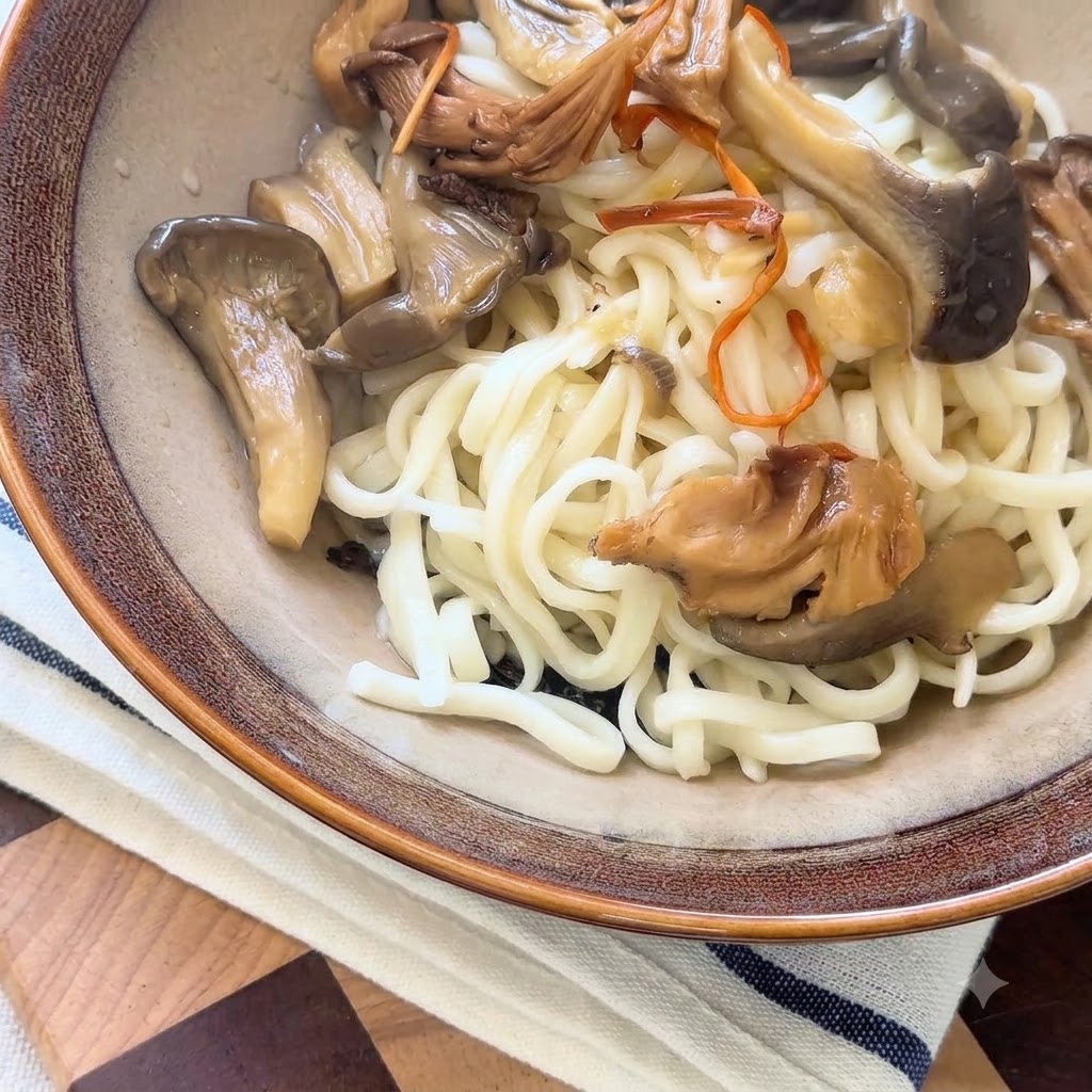 Hot mushroom broth and savory cooked mushrooms being ladled over noodles in a serving bowl.