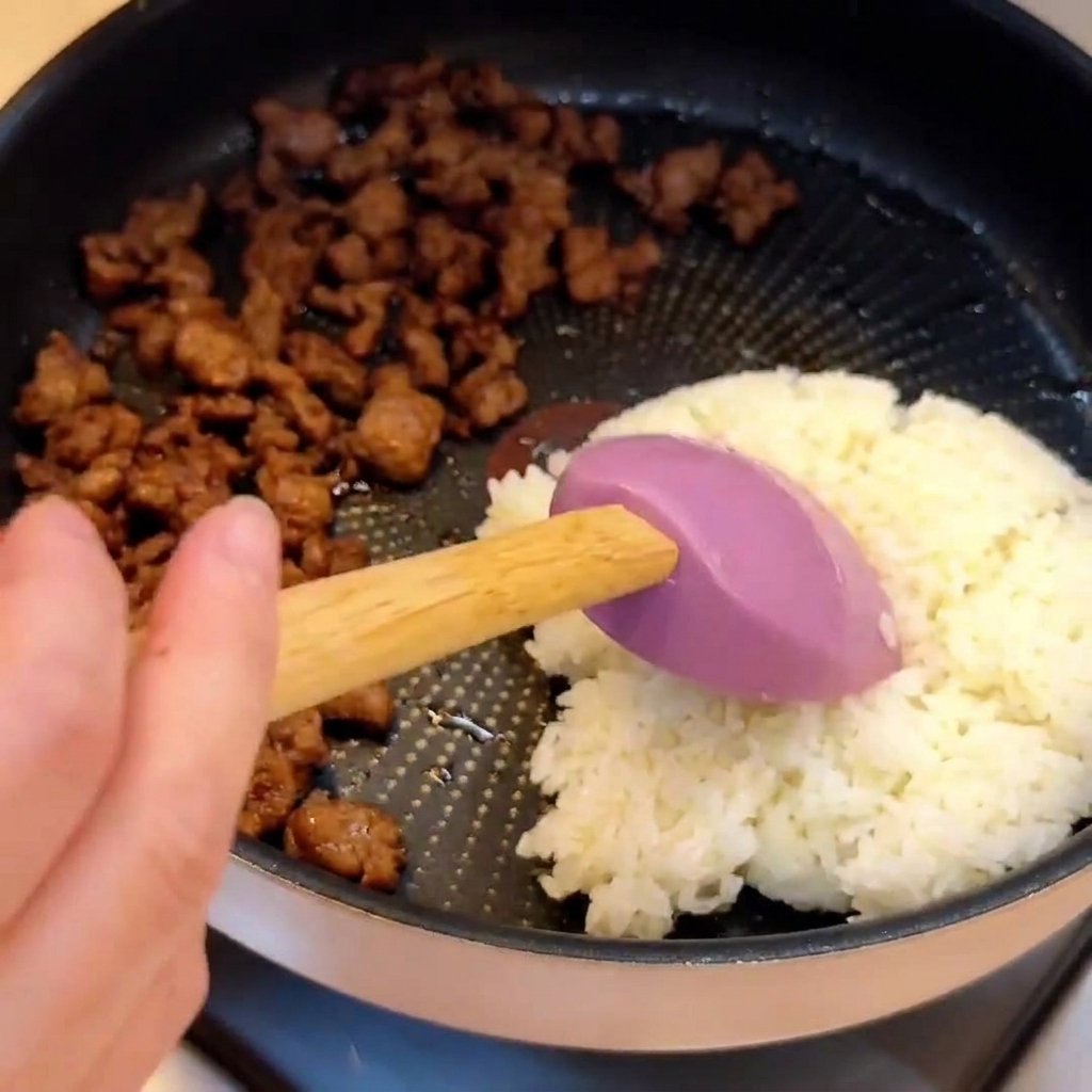 Cooked white rice placed next to cooked ground beef inside a frying pan.