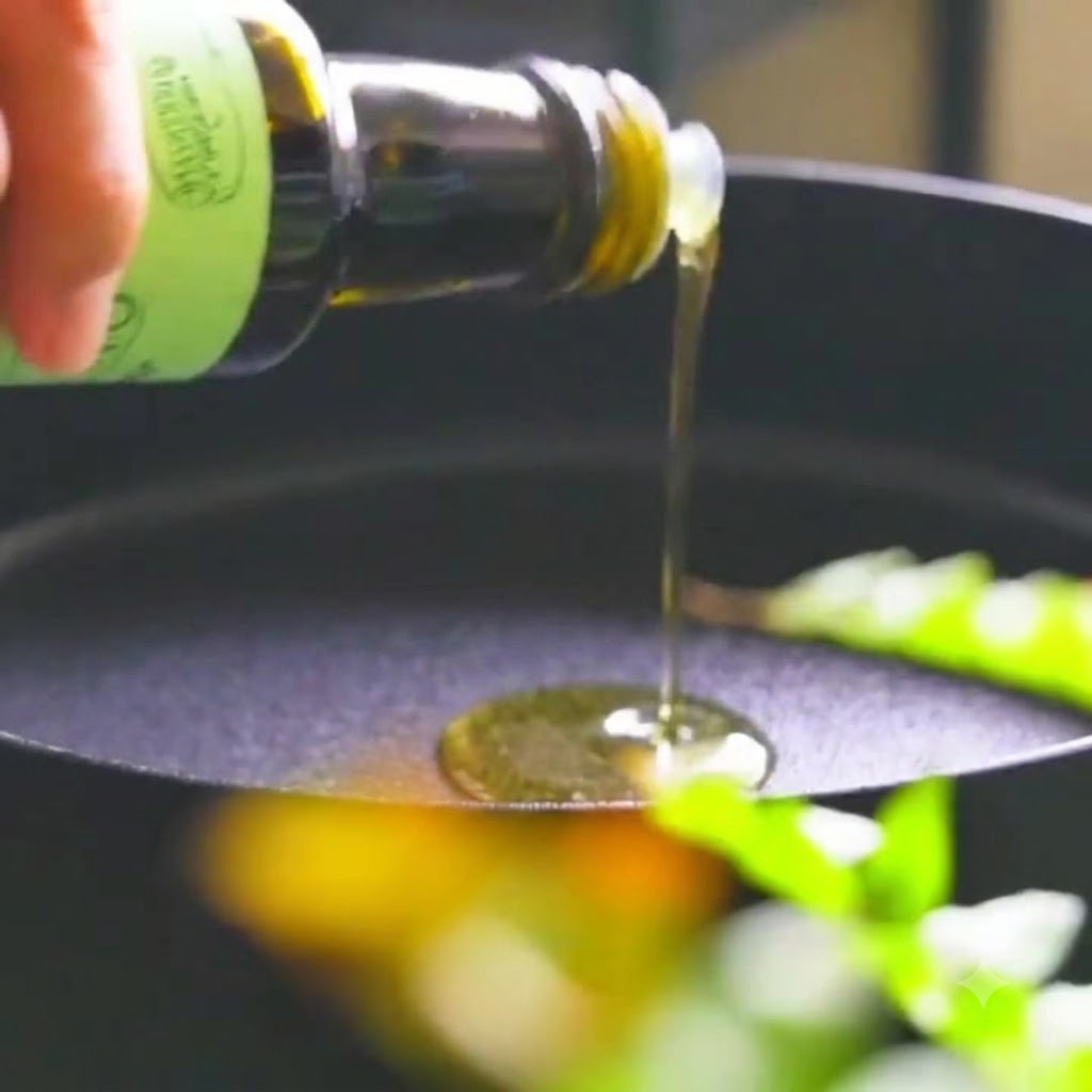 Oil being poured from a bottle into a frying pan containing onions.