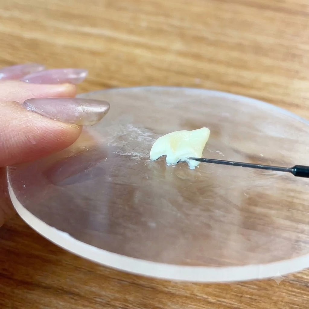 A needle tool detailing the surface of a sculpted clay piece.