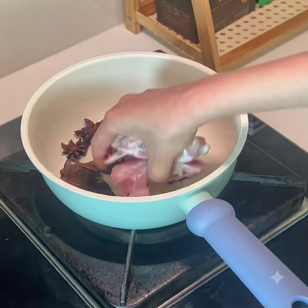 Pork ribs being placed by hand into a pot with oil and spices.