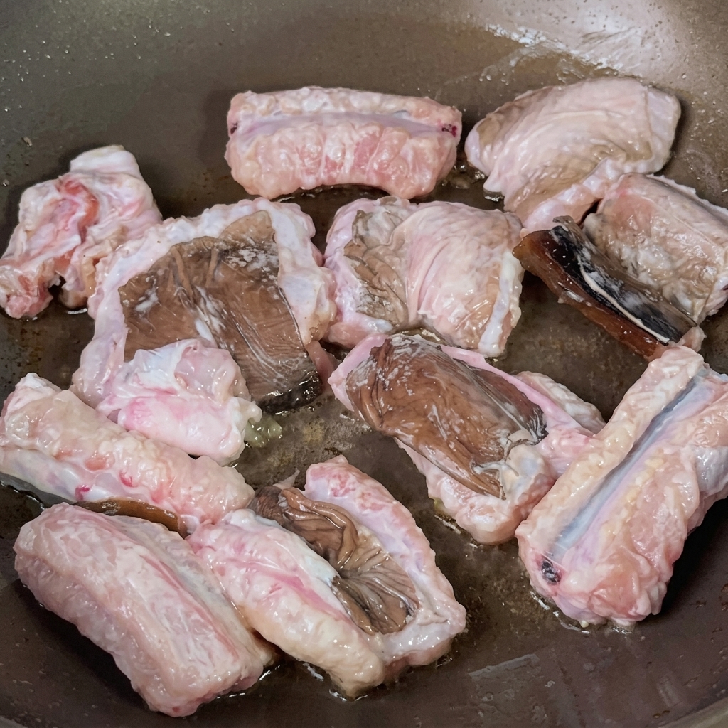 Eel pieces sizzling and frying in a cooking pan.