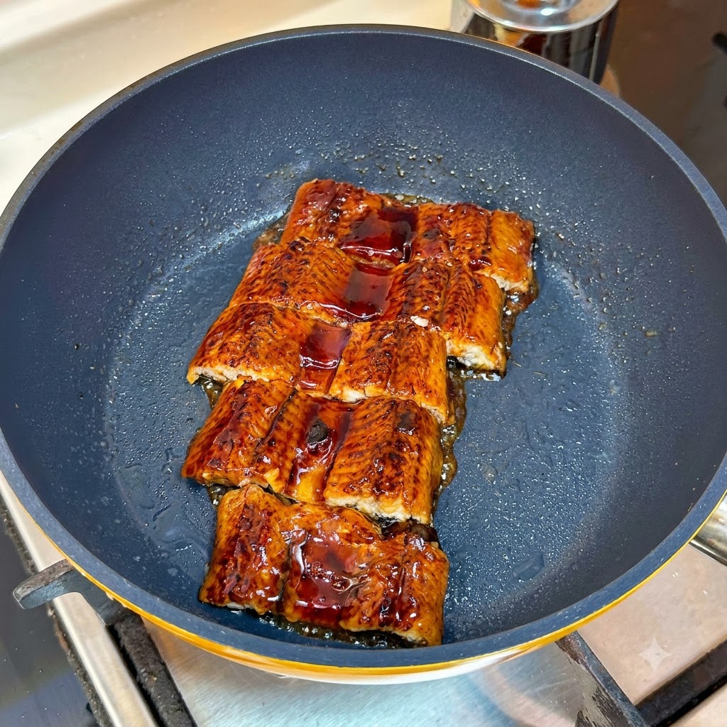 Sliced roasted eel simmering in a pan coated with a dark glossy glaze.