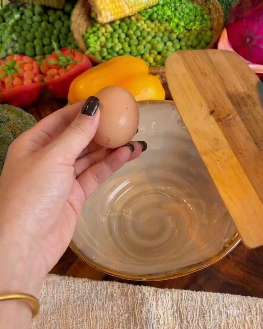 Two eggs cracked inside a ceramic bowl with milk being poured in.