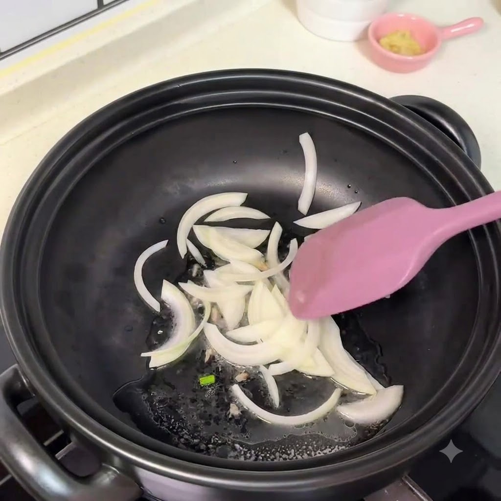 Sliced white onions being moved around a pot with a purple spatula.