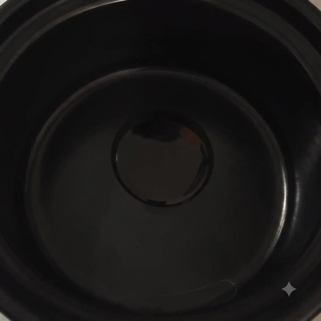 Chopped green onions and cooking oil sizzling inside a dark earthenware pot.