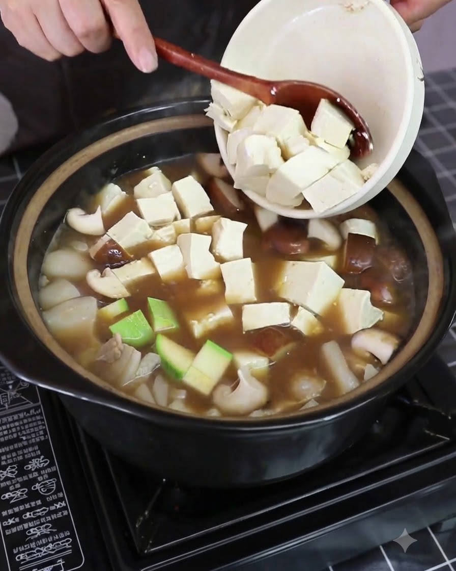 Fresh napa cabbage pieces being added into the simmering pot containing vegetables and tofu.